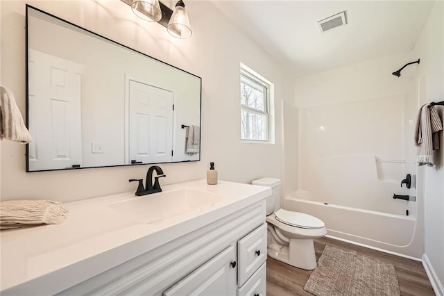 bathroom with visible vents, vanity, wood finished floors, bathing tub / shower combination, and toilet