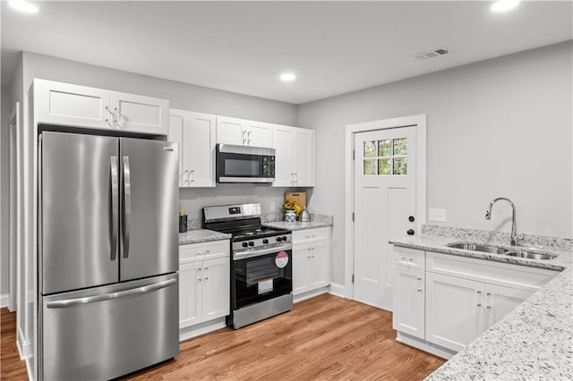 kitchen with sink, light hardwood / wood-style flooring, white cabinets, and appliances with stainless steel finishes