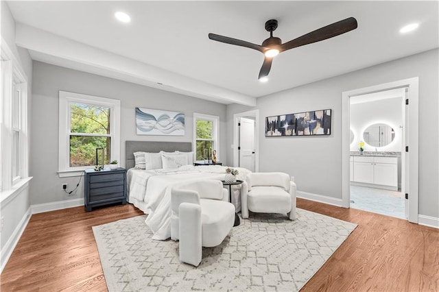 bedroom featuring hardwood / wood-style flooring, ensuite bathroom, ceiling fan, and multiple windows