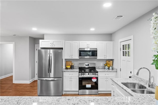 kitchen featuring white cabinetry, appliances with stainless steel finishes, sink, and light stone counters