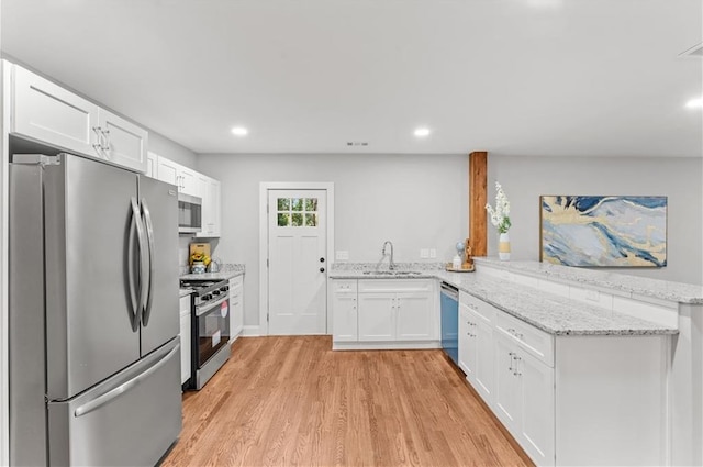 kitchen featuring sink, light hardwood / wood-style flooring, appliances with stainless steel finishes, white cabinetry, and kitchen peninsula