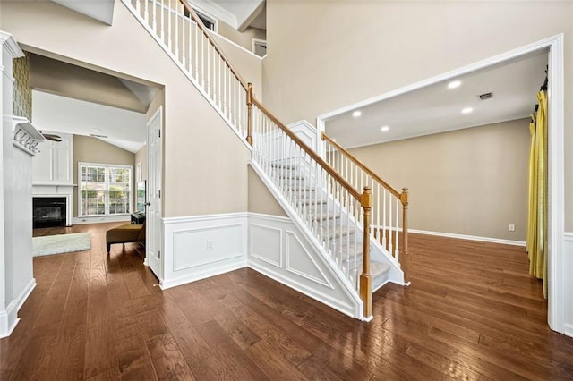 stairway with a towering ceiling and hardwood / wood-style floors