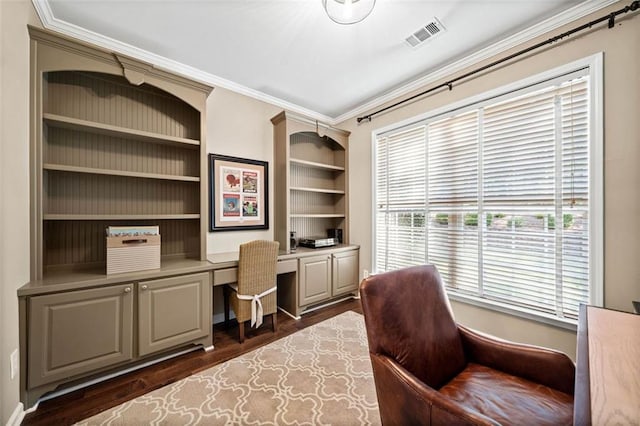 office area with ornamental molding, built in desk, and dark hardwood / wood-style flooring