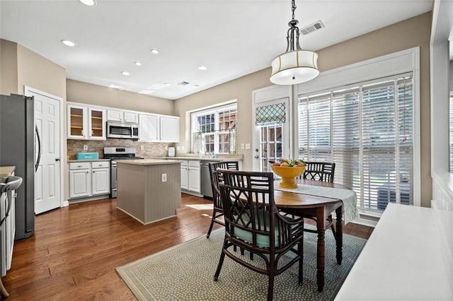 kitchen featuring white cabinetry, a center island, dark hardwood / wood-style floors, pendant lighting, and stainless steel appliances