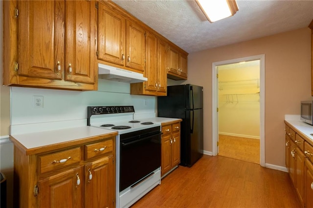 5425 Windswept Trce, Sugar Hill, GA 30518 - kitchen with under cabinet range hood, electric range, freestanding refrigerator, brown cabinetry, and a textured ceiling