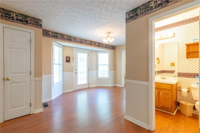 5425 Windswept Trce, Sugar Hill, GA 30518 - unfurnished dining area featuring light wood finished floors, a chandelier, a sink, a textured ceiling, and baseboards