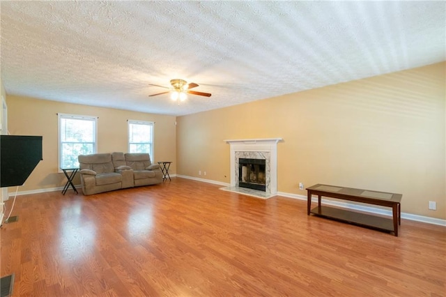 5425 Windswept Trce, Sugar Hill, GA 30518 - living area featuring a fireplace, a ceiling fan, a textured ceiling, light wood-style flooring, and baseboards