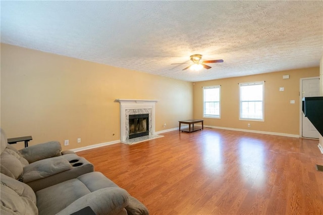 5425 Windswept Trce, Sugar Hill, GA 30518 - living room with a ceiling fan, a textured ceiling, light wood finished floors, baseboards, and a premium fireplace