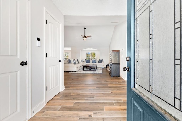 entryway with vaulted ceiling, light wood-style floors, baseboards, and ceiling fan