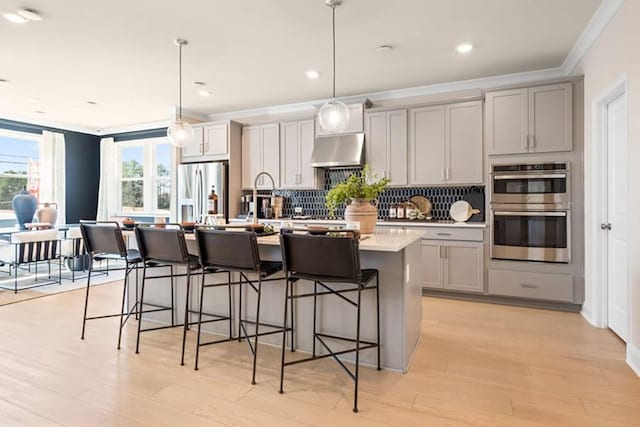 1446 Auburn Glen Rd, Dacula, GA 30019 - kitchen with appliances with stainless steel finishes, gray cabinets, ornamental molding, a center island with sink, and a kitchen breakfast bar