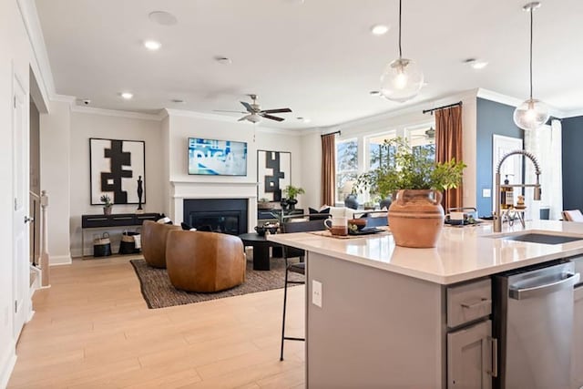 kitchen with pendant lighting, sink, ceiling fan, stainless steel dishwasher, and light hardwood / wood-style flooring