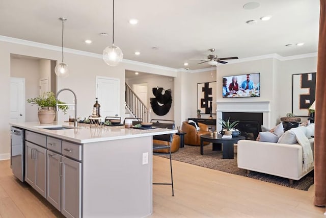 kitchen with a center island with sink, ceiling fan, gray cabinetry, decorative light fixtures, and sink