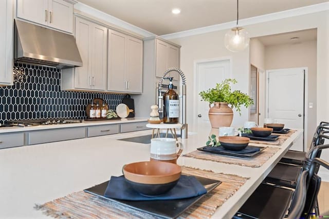 kitchen with backsplash, hanging light fixtures, stainless steel gas cooktop, gray cabinetry, and crown molding