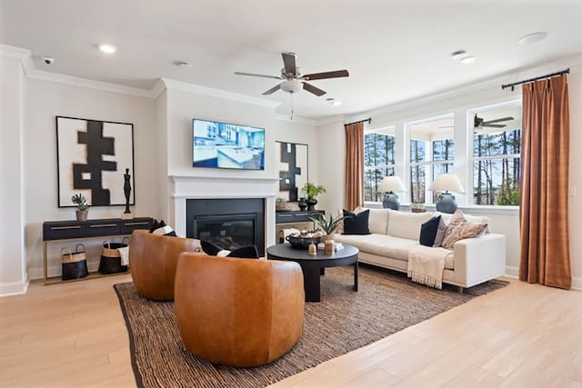 living room with ceiling fan, ornamental molding, and light wood-type flooring