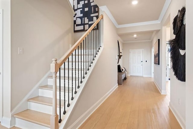 foyer entrance with ornamental molding and light hardwood / wood-style floors