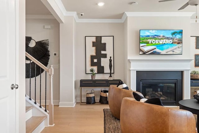 living room featuring ceiling fan, ornamental molding, and light hardwood / wood-style floors