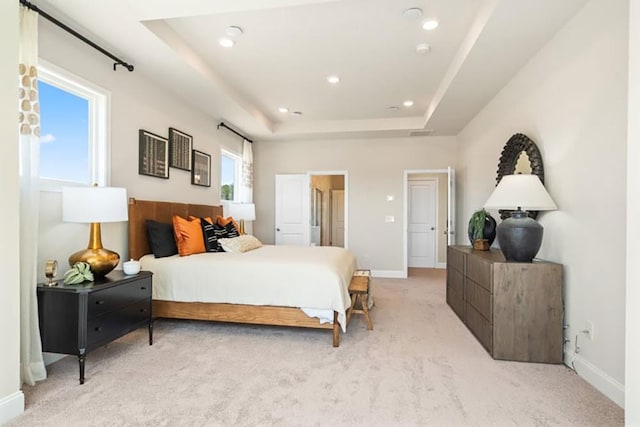 bedroom featuring a tray ceiling and light carpet