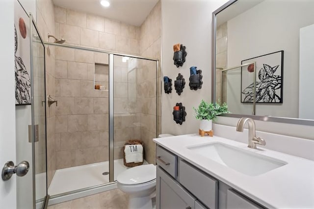 bathroom with vanity, toilet, tile patterned floors, and a shower with door