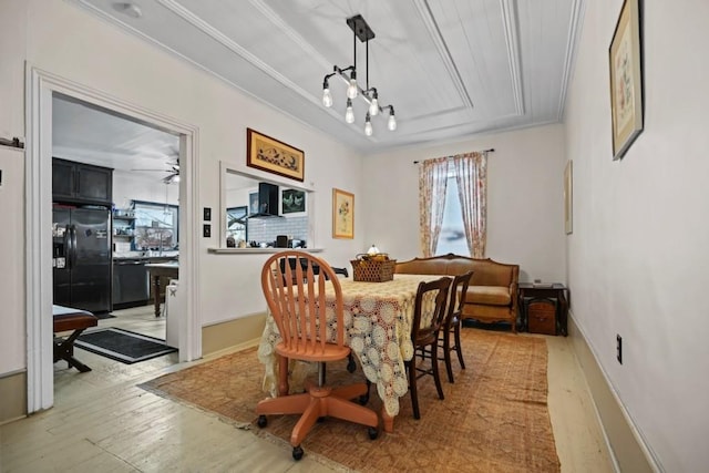 dining space featuring a raised ceiling, crown molding, and light hardwood / wood-style floors