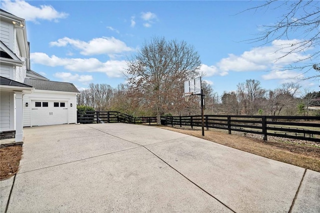 view of patio featuring fence, driveway, and a garage
