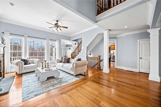 living area featuring baseboards, wood finished floors, ornate columns, and ceiling fan