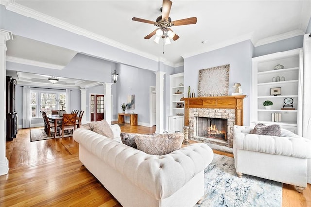 living room featuring ceiling fan, crown molding, light wood finished floors, and ornate columns