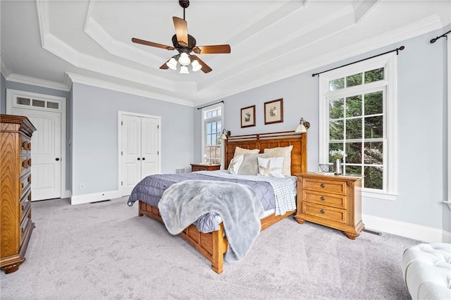 carpeted bedroom featuring a raised ceiling, visible vents, baseboards, a closet, and ornamental molding