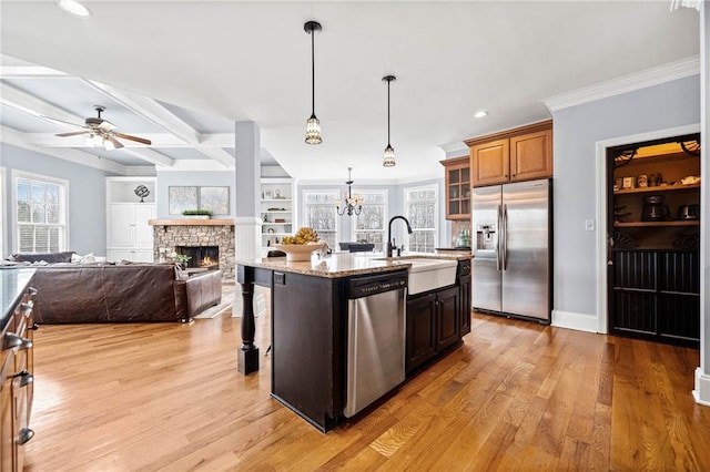 kitchen with a sink, light stone countertops, a fireplace, a kitchen bar, and appliances with stainless steel finishes