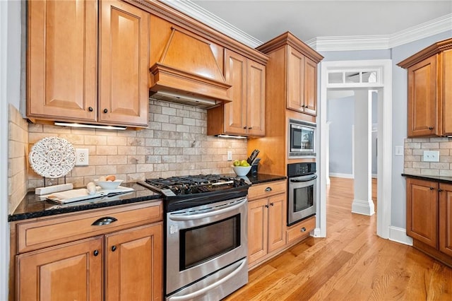 kitchen featuring stainless steel appliances, light wood finished floors, custom range hood, backsplash, and baseboards