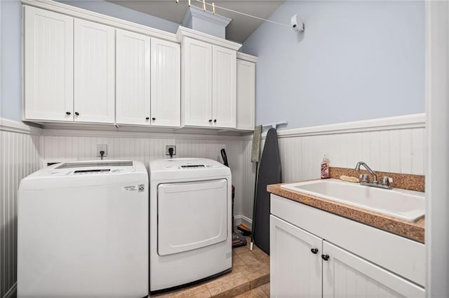 laundry room with cabinet space, independent washer and dryer, wainscoting, and a sink