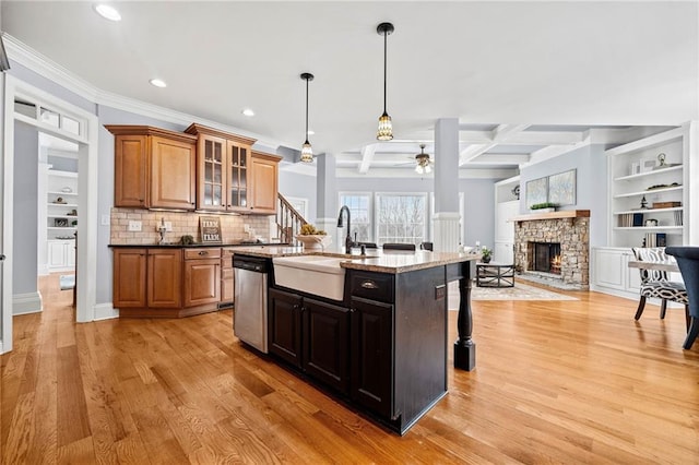 kitchen featuring a sink, light wood-type flooring, ceiling fan, dishwasher, and a fireplace