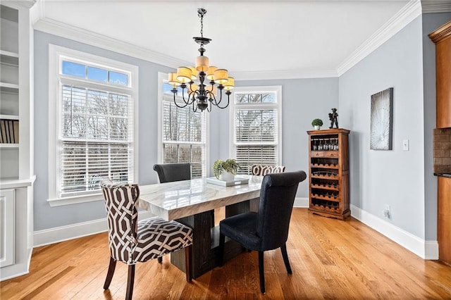 dining area featuring light wood finished floors, ornamental molding, a wealth of natural light, baseboards, and a chandelier