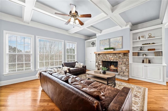living area featuring a stone fireplace, beam ceiling, ceiling fan, and coffered ceiling