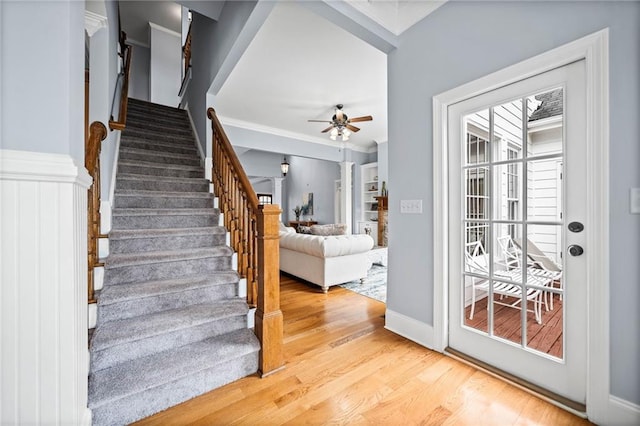 stairway featuring ornamental molding, baseboards, a ceiling fan, and wood finished floors