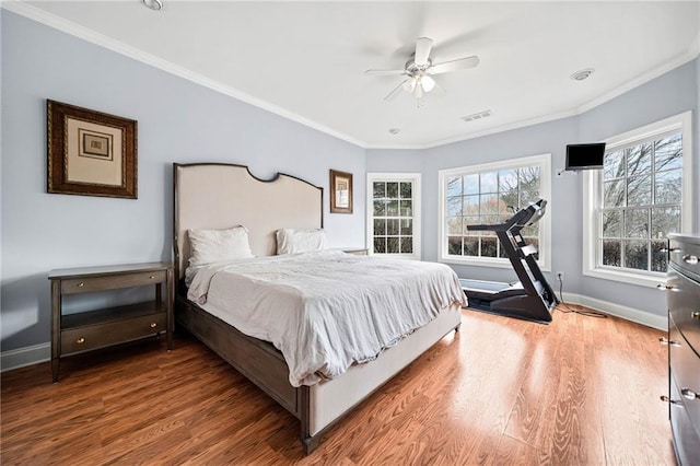 bedroom with wood finished floors, visible vents, baseboards, and ornamental molding