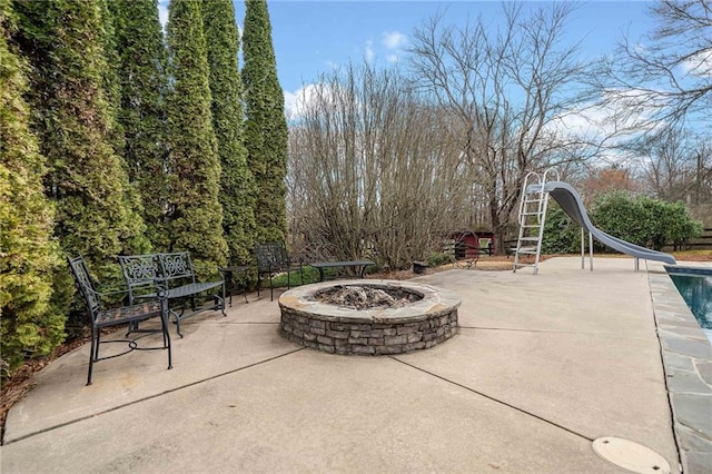 view of patio with an outdoor pool and an outdoor fire pit