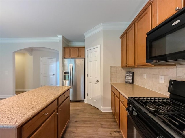750 Summerstone Ln, Lawrenceville, GA 30044 - kitchen featuring black appliances, arched walkways, crown molding, tasteful backsplash, and brown cabinets