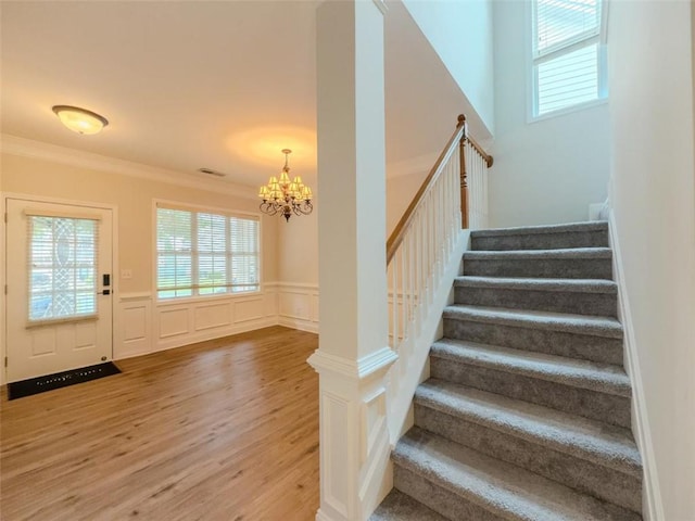 750 Summerstone Ln, Lawrenceville, GA 30044 - staircase featuring wood finished floors, healthy amount of natural light, a chandelier, ornamental molding, and a wainscoted wall