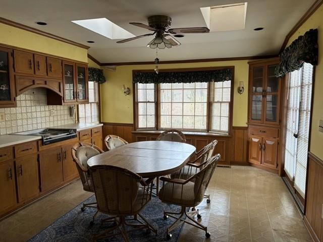 dining area with crown molding, ceiling fan, and wood walls