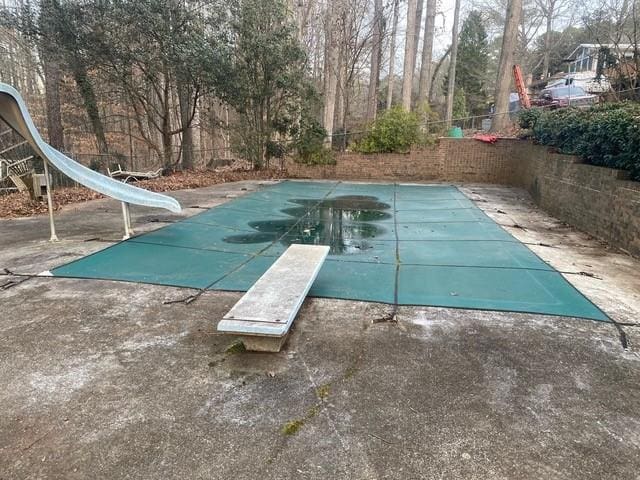 view of swimming pool with a water slide and a diving board