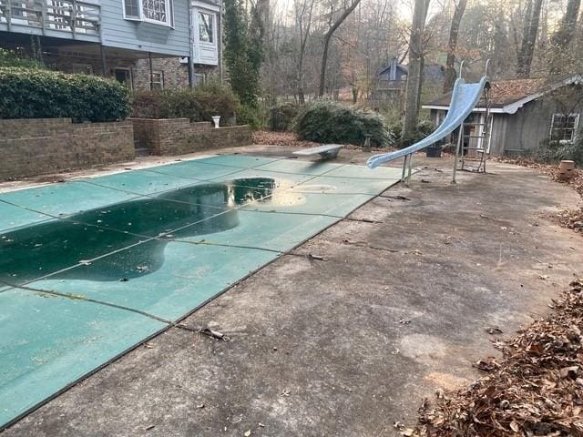 view of pool with a diving board and a water slide