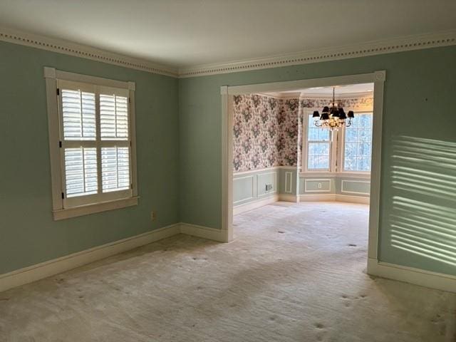 unfurnished room featuring crown molding, a healthy amount of sunlight, carpet floors, and a notable chandelier