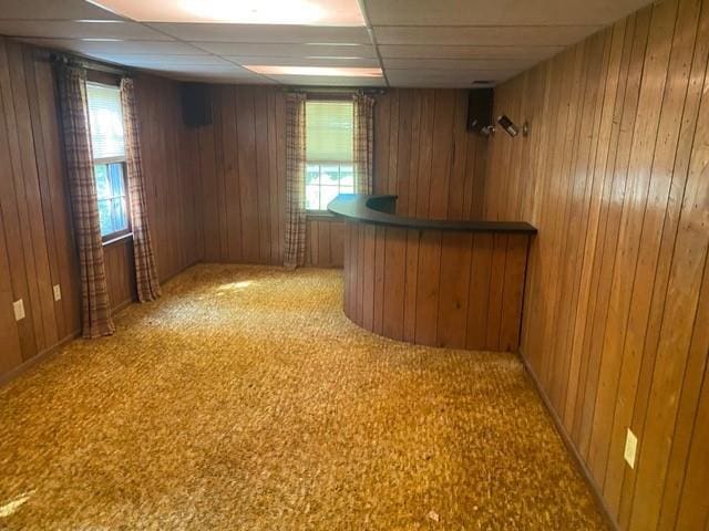 bar featuring wooden walls, carpet, and a paneled ceiling