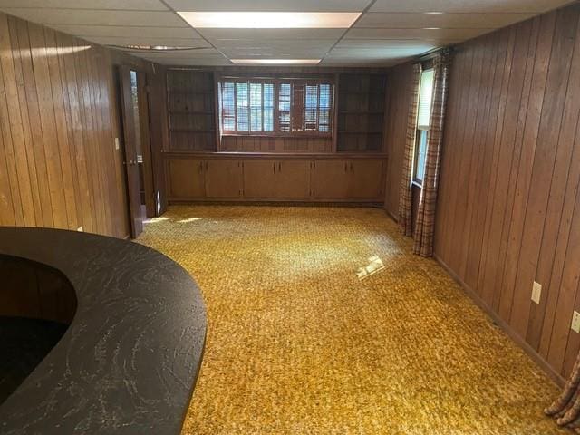 spare room featuring a drop ceiling and wooden walls