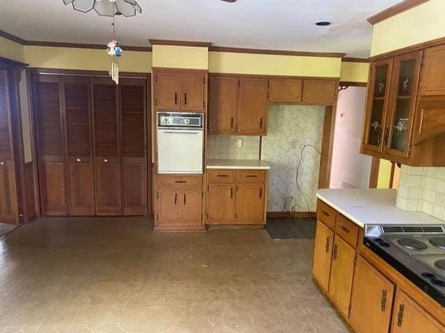 kitchen with cooktop, crown molding, white oven, and tasteful backsplash