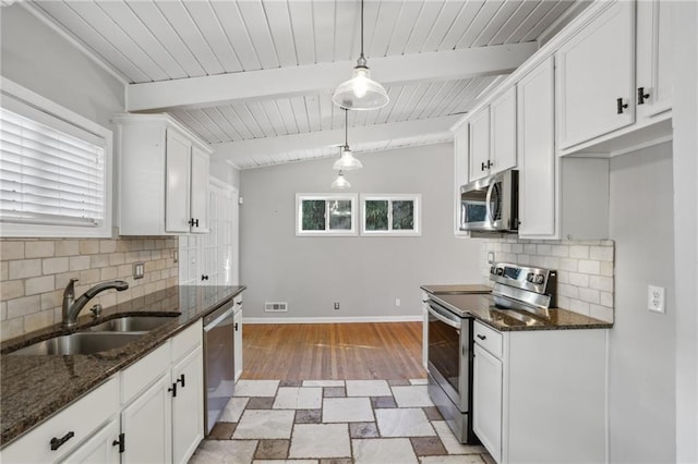 kitchen featuring sink, appliances with stainless steel finishes, hanging light fixtures, lofted ceiling with beams, and white cabinets