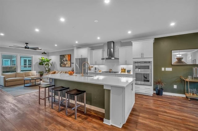 2066 Patterson Park Rd, Decatur, GA 30033 - kitchen featuring wall chimney exhaust hood, appliances with stainless steel finishes, a spacious island, a breakfast bar area, and light countertops