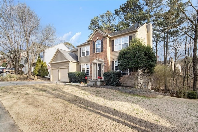 colonial house with brick siding, driveway, an attached garage, and a chimney