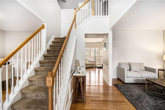 stairway with baseboards, a high ceiling, and wood finished floors