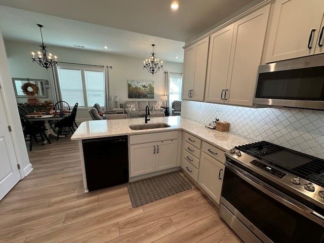 kitchen with kitchen peninsula, sink, stainless steel appliances, and decorative light fixtures